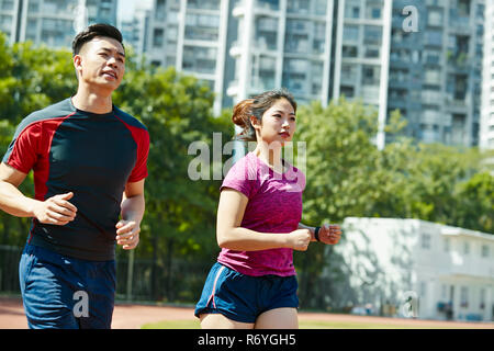 young asian man and woman training running on track in stadium Stock Photo