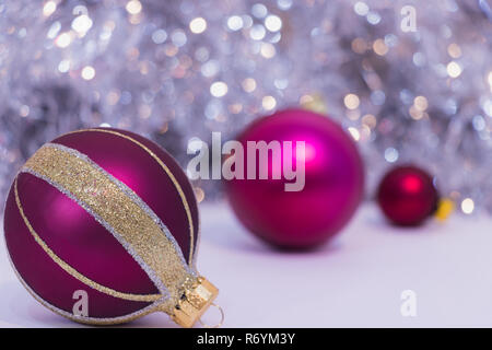 Three Christmas Balls on a sparkling silver background - Purple and Red XMAS balls, bokeh, lights in the background Stock Photo
