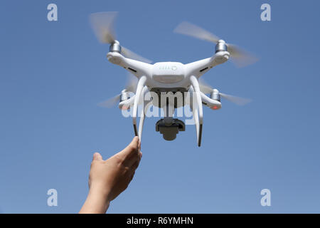 Hand catching drone aircraft in blue sky background Stock Photo
