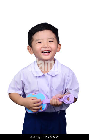 Asian Thai kindergarten student kid in school uniform playing toy guitar isolated on white background with clipping path. musical concept idea. Stock Photo