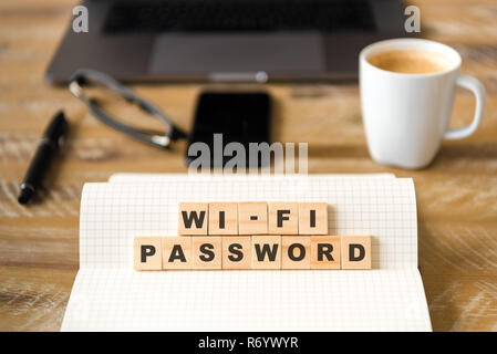 Closeup on notebook over wood table background, focus on wooden blocks with letters making WI-FI PASSWORD words Stock Photo