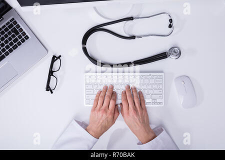Elevated View Of A Doctor's Hand Typing On Computer Keyboard Stock Photo