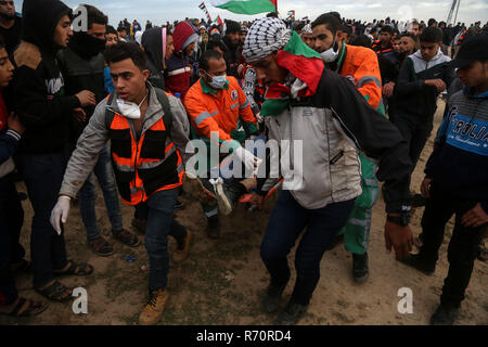 Gaza, Palestine. 7th December 2018.Palestinian medics carry a wounded man during clashes with Israeli troops on the Gaza-Israel border, east of Gaza City, on Dec. 7, 2018. At least 33 Palestinians were shot and wounded by Israeli soldiers' gunfire during clashes with Palestinian protesters in eastern Gaza Strip, close to the border with Israel, medics said. Credit: Stringer/Xinhua/Alamy Live News Stock Photo