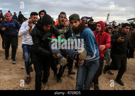 Gaza, Palestine. 7th December 2018.Palestinian medics carry a wounded man during clashes with Israeli troops on the Gaza-Israel border, east of Gaza City, on Dec. 7, 2018. At least 33 Palestinians were shot and wounded by Israeli soldiers' gunfire during clashes with Palestinian protesters in eastern Gaza Strip, close to the border with Israel, medics said. Credit: Stringer/Xinhua/Alamy Live News Stock Photo