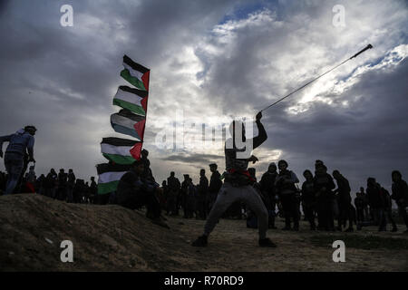 Gaza, Palestine. 7th December 2018.A Palestinian protester uses a slingshot to hurl stones at Israeli troops during clashes on the Gaza-Israel border, east of Gaza City, on Dec. 7, 2018. At least 33 Palestinians were shot and wounded by Israeli soldiers' gunfire during clashes with Palestinian protesters in eastern Gaza Strip, close to the border with Israel, medics said. Credit: Stringer/Xinhua/Alamy Live News Stock Photo