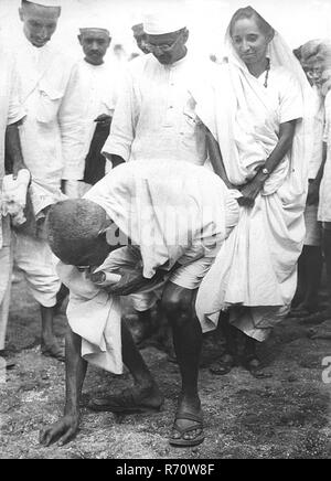 Mahatma Gandhi breaking salt law by picking up lump of natural salt at Dandi, Gujarat, India, April 6, 1930, 8.30 a.m.