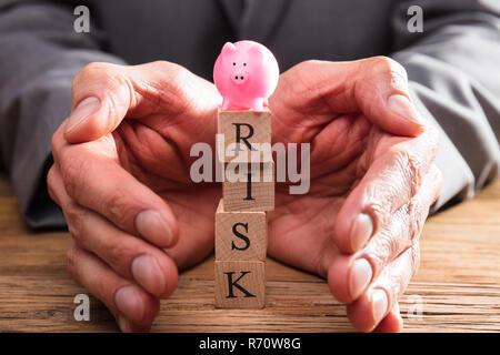 Businessperson Protecting Wooden Blocks With Risk Word Stock Photo