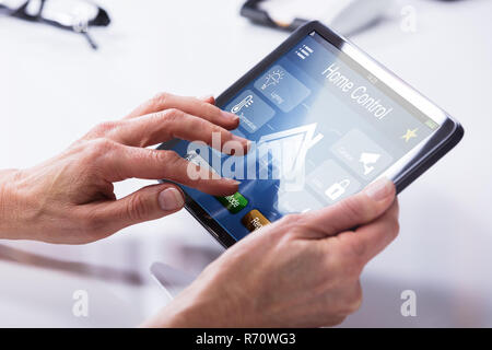 Person Using Home Control System On Digital Tablet Stock Photo