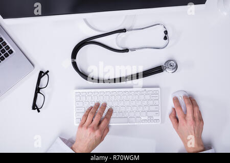 Elevated View Of A Doctor's Hand Typing On Computer Keyboard Stock Photo