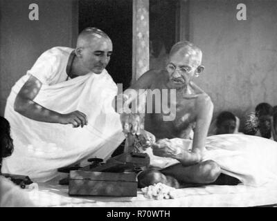 Mahatma Gandhi repairing his charkha spinning wheel, with Madeleine Slade, named Mirabehn, Sevagram Ashram, Wardha, Maharashtra, India, 1936, old vintage 1900s picture Stock Photo