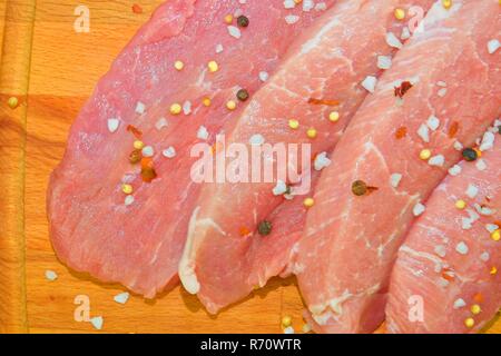 Pork chops with spices on a cutting board. Slices of pork steaks. Pork chops ready to fry Stock Photo