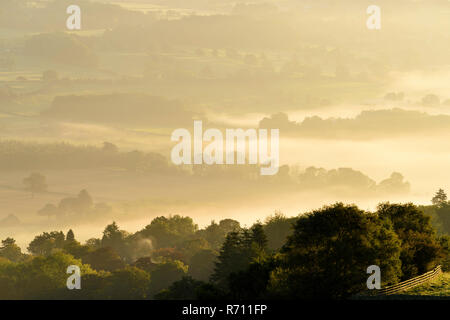 Long-distance, foggy, early morning view over scenic rural Wharfedale, the valley shrouded in mist or fog - near Ilkley, West Yorkshire, England, UK Stock Photo