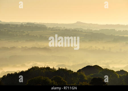 Long-distance, foggy, early morning view over scenic rural Wharfedale, the valley shrouded in mist or fog - near Ilkley, West Yorkshire, England, UK Stock Photo