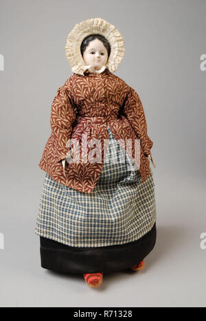 mw. Andres-Van Embden, Dollhouse doll, papier-mâché head with inlaid brown glass eyes, wooden forearms, fabric body and legs, dressed in ankle-length black skirt, reddish-brown bodice and blue-white checkered apron, doll model papier maché wood glass leather plaster? cotton linen tulle, sewn crochet textile Doll house doll representing kitchen maid in work clothes. Woman with papier-mâché head and painted face with inlaid brown glass eyes. Long narrow hands of very light pink painted wood. The hair is painted and dull black in color. On the head hat of white piqué cotton with pleated strip wit Stock Photo