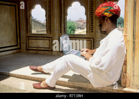 Rajasthani man operating laptop computer outside house, Pushkar, Rajasthan, India, Asia, MR Stock Photo