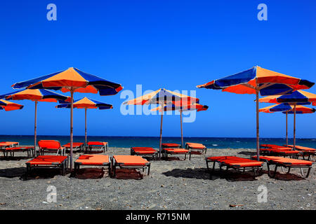 Colourful beach chairs and umbrellas on beach, blue sea, Crete, Greece Stock Photo