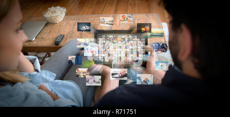 Couple using tablet for watching VOD service. Video On Demand television with abstract flying images Stock Photo