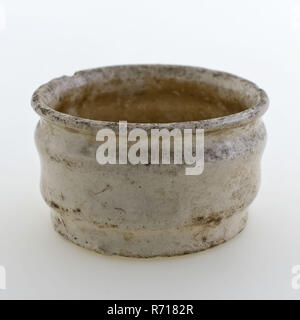 Pottery ointment jar, low model, white glazed, ointment jar pot holder soil find ceramic earthenware glaze tin glaze, delft white hand-turned glazed baked Pottery ointment jar wide low form with two smooth nips along the outside of the kettle. Obliquely outward-facing edge. White glazed. Stand area with deducting rails. Pot is slightly deformed archeology Rotterdam Bombazijnen cemetery health care indigenous pottery pharmacy packaging medicine drug sell craft store soil find: found Bombazijnen Kerkhof 1905. Stock Photo