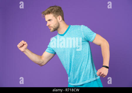 Man in tshirt and shorts on violet background. Runner in blue casual clothes on purple background. Sportsman in active wear for running. Sport fashion style and trend. Fitness and gym activity. Stock Photo