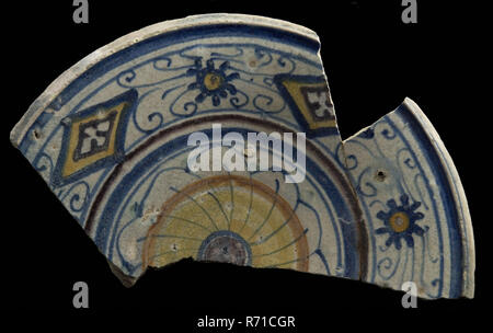 Fragment majolica dish, polychrome, rosette in the middle, diamond pattern in the edge, dish plate crockery holder soil find ceramic earthenware glaze, pt 3.5 baked underside covered with clear lead glaze Polychrome. Distorted edge during drying. Coarse-leaf rosette in the mirror diamond figures in the edge alternated with small blue wheel with an orange core Yellow shard some shredded pottery archeology Rotterdam food decorate archaeological find in the soil Rotterdam 1941. Stock Photo