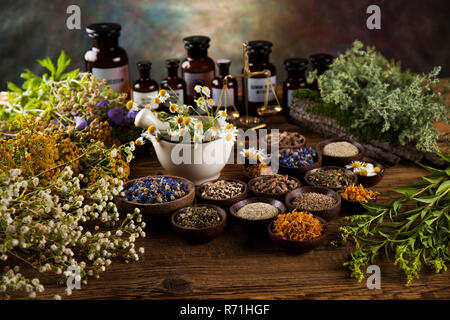 Healing herbs on wooden table, mortar and herbal medicine Stock Photo