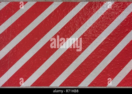 Sticker texture with red and white stripes diagonally on a concrete surface. Stock Photo