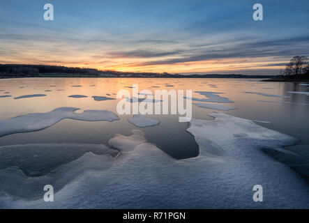 Scenic winter landscape with frozen lake, sunset and beautiful evening light in Finland Stock Photo