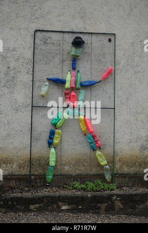 Fun and good way of recycling old plastic bottles with a statue of a person on a wall Stock Photo