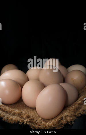 Eggs in a nest on hemp sack, dark corner. Stock Photo