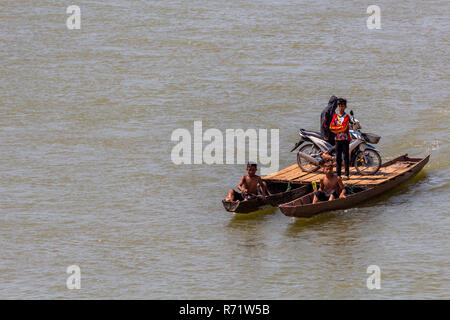 Don Daeng, Laos - April 27, 2018: Group of children transporting a scooter on a catamaran ferry made of two wooden canoes Stock Photo