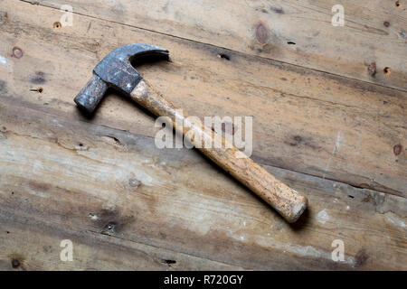 A wooden handled claw hammer on a rough wood surface. Stock Photo