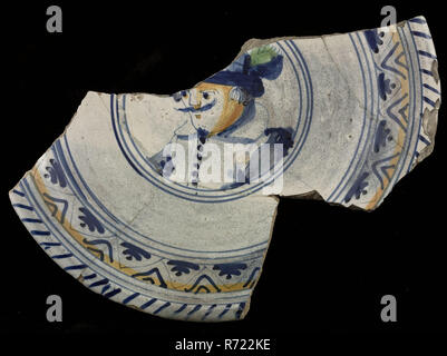 Fragment majolica dish with polychrome image of man with hat, plate crockery holder soil find ceramic earthenware glaze tin glaze lead glaze, hand-turned baked glazed painted Glued fragment of majolica dish with as central representation the bust of man with hat Tapestry over the edge Polychrome decor Under the edge frieze with zigzag line and filled triangles Bottom covered with bright lead glaze Cooked on prunes. Standring No or hardly used archeology serve serving food Stock Photo