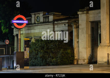 London, England, UK - October 15, 2018: A London Underground tube roundel is illuminated at night marking an entrance to Hyde Park Corner tube station Stock Photo