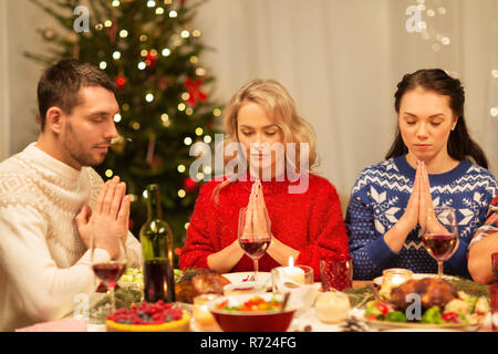 friends praying before christmas dinner at home  Stock Photo