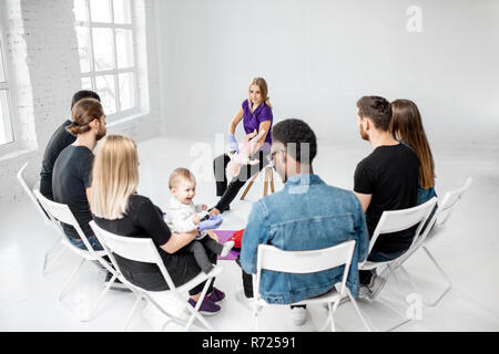 Group of people during the training with instructor showing on baby dummy how to provide first aid to the suffocating child Stock Photo