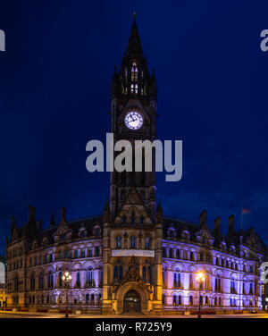 Manchester, England, UK - July 1, 2018: The gothic exterior and clock tower of Manchester Town Hall is lit at night on the city's Albert Square. Stock Photo