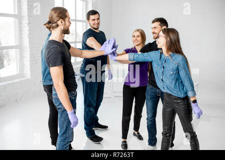 Portrait of a young team of students or coworkers touching hands together after the first aid training in the white classroom Stock Photo