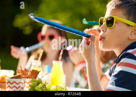 kids blowing party horns on birthday in summer Stock Photo