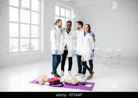 Portrait of a young team of medics in uniform standing together with medical stuff after the first aid training in the white classroom Stock Photo