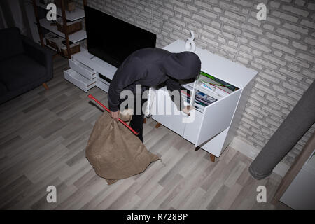 Elevated View Of Thief With Crowbar And Sack Stealing File From Shelf Stock Photo