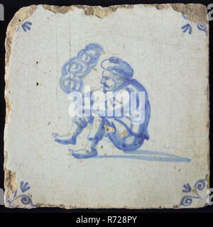 Tile with seated man with beret holding smoking tube or wooden trowel in the hand and or lighting or tapping, corner motif, ox-head, wall tile tile sculpture ceramic earthenware glaze, baked 2x glazed painted Yellow shard square. Blue on white background Tile with seated man with beret holding smoking tube or wooden trowel in the hand and or lighting or tapping Angle pattern ox head fire smoke headgear Stock Photo