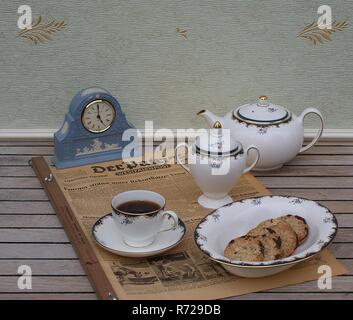 English tea set in front of a pale blue Wedgwood watch, Jasperware, with applied relief plate of white clay, on an old German daily newspaper Stock Photo