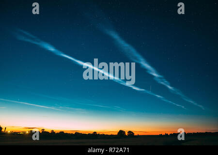 Night Starry Sky And Noctilucent Clouds Above Summer Meadow Landscape. Glowing Stars And Night Shining Clouds. Tenuous Cloud-like Phenomena In The Upp Stock Photo