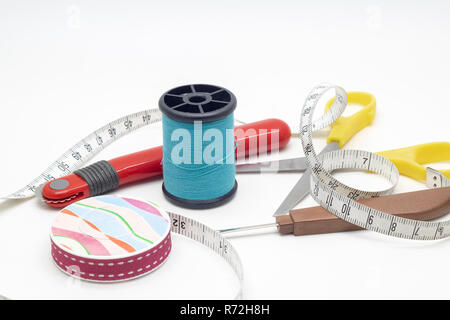 Thread, Scissors, Thread picker, Tracing wheel, and measuring tape on white background. Stock Photo