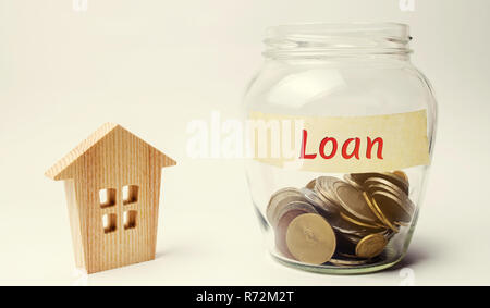 Glass jar with the inscription Loan and a small wooden house. Buying a home in debt. Family investment in real estate and risk management concept. Loa Stock Photo