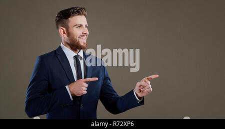 Handsome man in suit pointing away Stock Photo