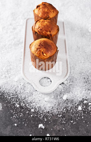 Traditional Christmas mini Panettone with raisins and dried fruits on white serving plate over snow on concrete table. Stock Photo