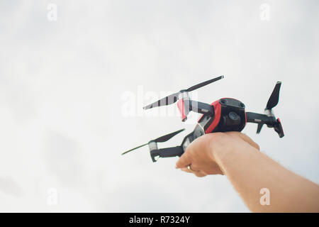 A man, a professional aerial photographer, launches a quadcopter or drone in the sky to take a video or photo of a terrain from a height. Man operatin Stock Photo