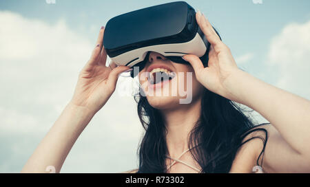 Happy girl using VR headset. The future. Woman with glasses of virtual reality. Digital future and innovation. Woman getting experience using VR-headset glasses. Visual reality concept. Future is now Stock Photo