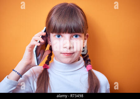 technology and communication, Caucasian teen girl talking on the phone on a colored background, place for text Stock Photo